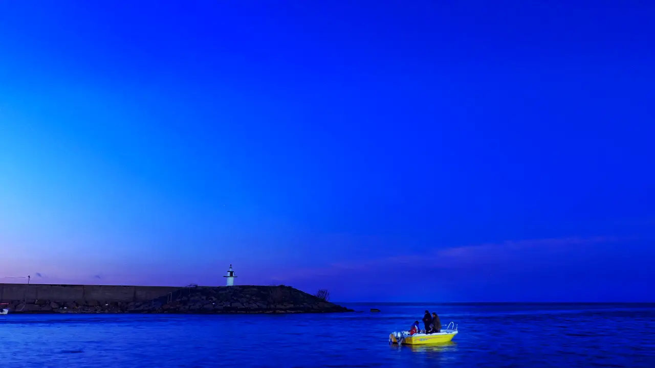 resimler-haber/Scenic_Blue_Hour_Landscape_with_a_Small_Yellow_Boat_and_Lighthouse_on_a__cJiKrdw.webp