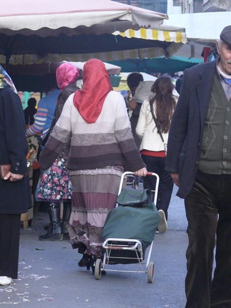 Pazar yerinde pazar arabasını süren bir kadın.