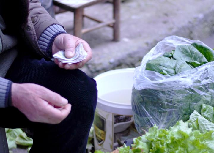 enflasyon oranları, pazar yerinde para uzatan bir pazarcı görseli